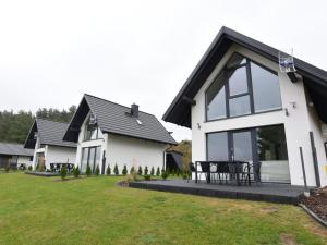 a white house with a black roof at Modern holiday homes directly on the lake in Kiedrowice in Kiedrowice