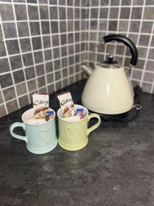 dos tazas de café sentadas en una barra con un hervidor de agua en Beach House Courtyard 1 Bed, en Southport