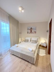 a white bedroom with a large bed and a window at 14 Gdynia Centrum - Apartament Mieszkanie dla 4 os in Gdynia