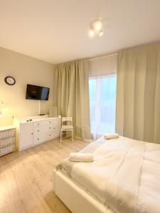a bedroom with a large white bed and a television at 14 Gdynia Centrum - Apartament Mieszkanie dla 4 os in Gdynia