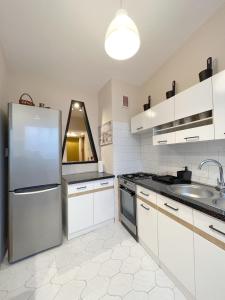 Una cocina con gabinetes blancos y un refrigerador de acero inoxidable. en 14 Gdynia Centrum - Apartament Mieszkanie dla 4 os, en Gdynia