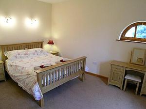 a bedroom with a bed and a desk and a window at The Stables in Filby