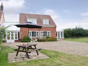 a picnic table with an umbrella in front of a house at Iris Apartment in Stalham