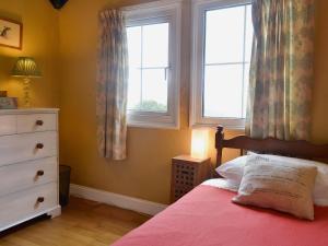 a bedroom with a bed with a dresser and two windows at Eastwood Lodge in Bath