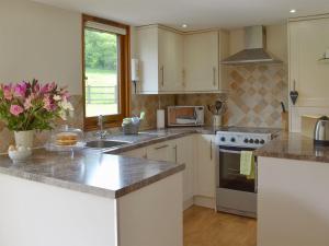 a kitchen with white cabinets and granite counter tops at Applebarrel Barn in Dunkeswell
