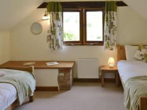 a bedroom with two beds and a desk and a window at Applebarrel Barn in Dunkeswell