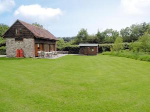 un gran patio con un edificio y un campo de césped en Applebarrel Barn en Dunkeswell
