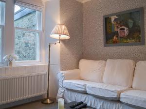 a living room with a white couch and a window at Garden Cottage in Strachur