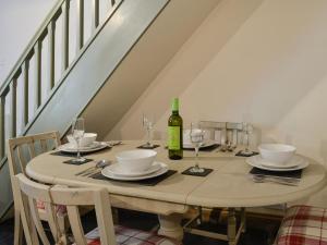 een eettafel met een fles wijn en glazen bij Maybill Cottage in Penmachno