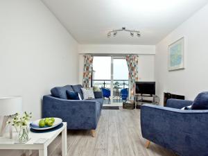 een woonkamer met twee blauwe banken en een tafel bij Fistral Escape in Crantock