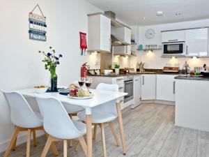 een keuken en eetkamer met een witte tafel en stoelen bij Fistral Escape in Crantock