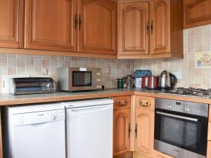 a kitchen with wooden cabinets and white appliances at Sparrows Nest in Preston