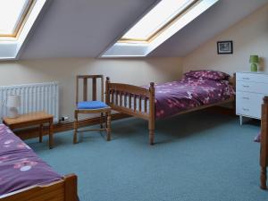 a attic bedroom with two beds and a chair at Fenham Barn in Soulby