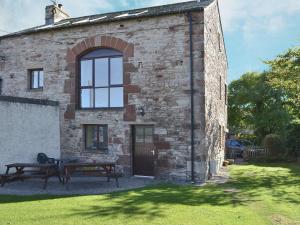 a brick building with a picnic table and a bench at Fenham Barn in Soulby