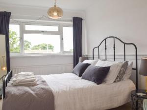 een slaapkamer met een bed met witte lakens en kussens bij Cartref in St. Davids