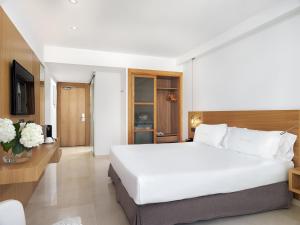 a bedroom with a large white bed and a television at Hotel Saratoga in Palma de Mallorca