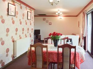 a dining room with a table with a vase of flowers on it at Elm View-w42961 in Gelliwen