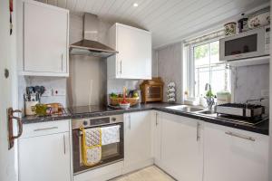 a kitchen with white cabinets and a stove top oven at The Garden Flat Ardullie in Ardullie