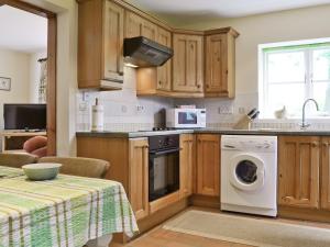 a kitchen with wooden cabinets and a washer and dryer at Garden Farm Cottage in Ilam