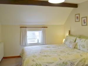 a bedroom with a large bed with a window at Garden Farm Cottage in Ilam