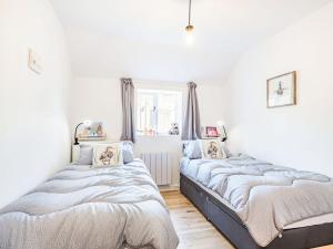 two beds in a room with white walls at Lucky Duck Cottage in Coltishall