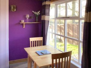 une salle à manger avec une table et un mur violet dans l'établissement New House Farm Annexe, à Neenton