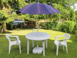 une table blanche avec deux chaises et un parasol dans l'établissement New House Farm Annexe, à Neenton