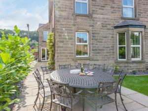 a patio with a table and chairs in front of a building at Haddon Villa in Bakewell
