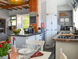 a kitchen with white cabinets and a table with a bottle of wine at Chapel Farm Cottage in Wetwang