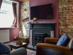a living room with a fireplace with a tv above it at Chapel Farm Cottage in Wetwang