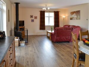 a living room with a red couch and a fireplace at Liftingstane Cottage in Closeburn