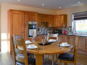 a kitchen with a wooden table with wine glasses on it at Liftingstane Cottage in Closeburn