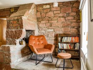 an orange chair sitting in front of a stone fireplace at Low Moat in Canonbie