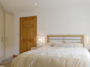 a bedroom with a white bed and a wooden door at Mickle Hill Mews in Gargrave