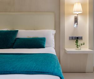 a bedroom with a bed with blue and white sheets at Hotel Saratoga in Palma de Mallorca