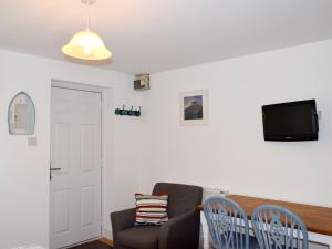 a living room with a chair and a tv at Farthings - 19292 in Bridport