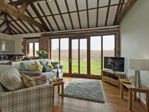 a living room with a couch and a tv at Elm Tree Barn in Felmingham