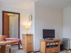 a living room with a television on a wooden cabinet at Magnolia Cottage in Ratley