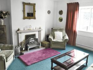 a living room with a fireplace and two chairs and a table at Penn Hill View in Aysgarth