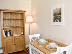 een eetkamer met een houten tafel met twee witte stoelen bij The Hollies in Bowness-on-Windermere