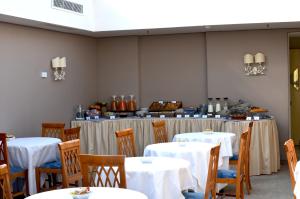uma sala de jantar com mesas e cadeiras com toalha de mesa branca em BeYou Hotel Ponte Milvio em Roma
