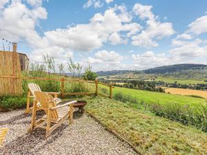 a wooden chair sitting on a gravel patio with a view of a field at Woodside Hut 1 - Uk36105 in Auchterneed