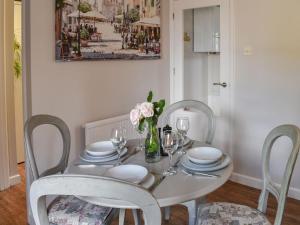 een witte eettafel met stoelen en een vaas met bloemen bij Hawks Mill Cottage in Needham Market
