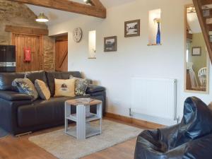 a living room with a leather couch and a table at The Chapel Barn in Llangynllo