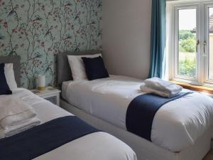 two beds in a room with a window at Hawks Mill Cottage in Needham Market