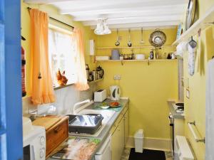 a small kitchen with yellow walls and a sink at Felicity Cottage in Staithes