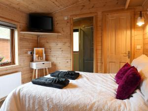 a bedroom with a bed in a wooden cabin at Astbury Falls Luxury Retreat in Eardington