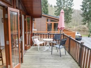 a deck with a table and chairs and an umbrella at Astbury Falls Luxury Retreat in Eardington