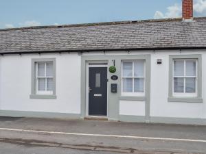 a white house with a black door and windows at Key To The Esk in Longtown