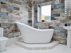 a bathroom with a white tub and a sink at Key To The Esk in Longtown